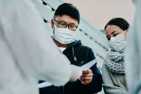 This permits us to travel. Shot of a young man talking to a healthcare worker in a hazmat suit during an outbreak.の素材 [FY310184855784]