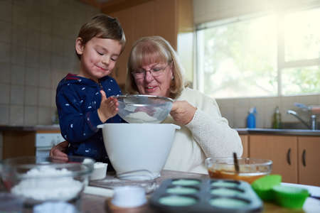 Baking fun with gran. Cropped shot of a woman baking with her grandson at home.の写真素材