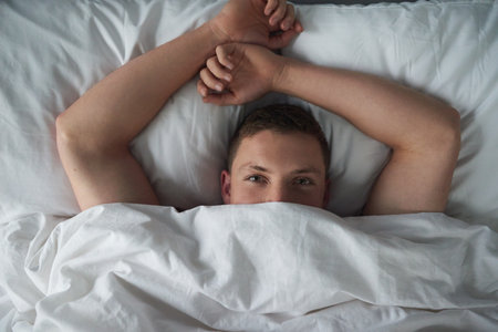 Cute and comfortable. Cropped shot of a shirtless young man relaxing in his bedroom.の写真素材