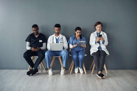 Sometimes, doctors risk their lives just save others. Shot of a group of doctors standing against a grey background at work.の写真素材
