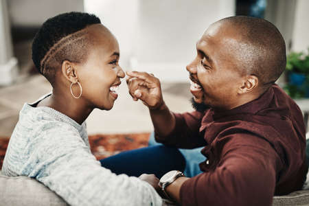 Lifes sweetest moments. Shot of a happy young couple spending time and relaxing together on a couch at home.の写真素材