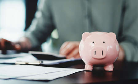 Saving up for a rainy day with my piggybank. Shot of an unrecognizable businessman doing paperwork...