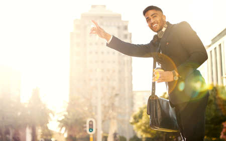 A cab for one please. Shot of a handsome young businessman hailing a cab.の写真素材
