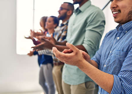 Success should always be celebrated. Cropped shot of a team of designers applauding together in an office.の写真素材