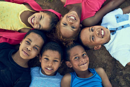 Kids will be kids. High angle portrait of children lying on the grass together outside.の写真素材