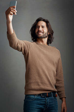 Celebrate yourself with a selfie. Studio shot of a handsome young man taking a selfie on his...