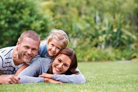 Having the best time with Mom and Dad. Portrait of a happy family of three lying outside on the...
