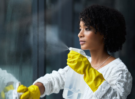 I guess its time to clean my windows. Shot of a young woman cleaning her windows.の写真素材