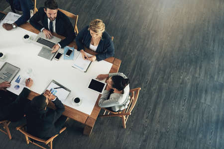 The business team to beat. High angle shot of a team of businesspeople working around a table in the office.の写真素材