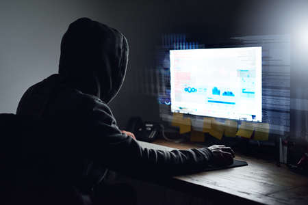 Unraveling the code. Rearview shot of a young programmer working on his computer late at night.