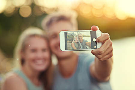Theyre always selfie ready. Cropped shot of a young couple taking a selfie together outside.の写真素材