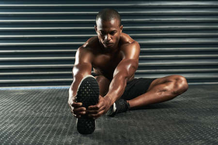 Getting nice and warm for his workout. Full length shot of an athletic young man going through his...