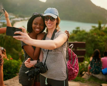 Our friends are going to be so jealous. Portrait of two happy friends taking a selfie on an island vacation.の写真素材
