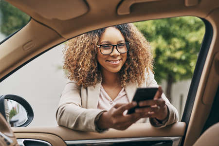 Letting everyone in the office know Im on my way. Shot of an attractive businesswoman using a cellphone on her morning commute.の写真素材