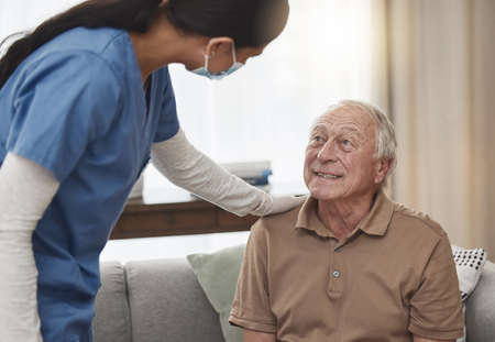 Im here for anything you need. Shot of a young female nurse having a checkup with an elderly patient at home.の写真素材