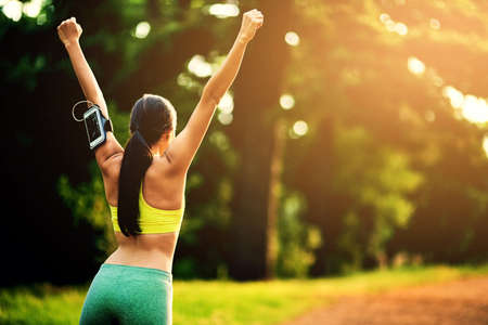 Keep on beating your personal best. Rearview shot of a sporty young woman celebrating a victory.の写真素材