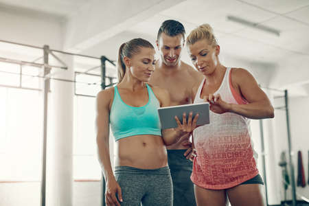 We should try this workout tutorial during our next session. Shot of a group of young people using a...