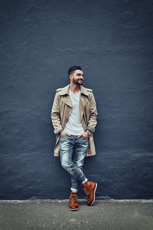 Style thats hot off the street. Shot of a fashionable young man wearing urban wear and posing against a gray wall.の写真素材