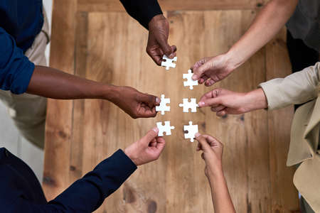 Theyre not puzzled by success. High angle shot of a group of unidentifiable businesspeople building a puzzle together in the office.の写真素材