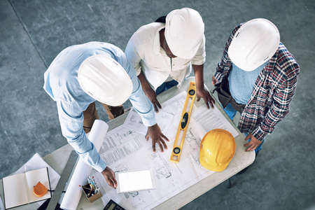 Taking clients designs to the next level. Shot of a group of builders having a meeting at a construction site.の写真素材