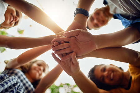 Theyll always be there for each other. Cropped shot of a happy family joining hands together in unity at the park.の写真素材