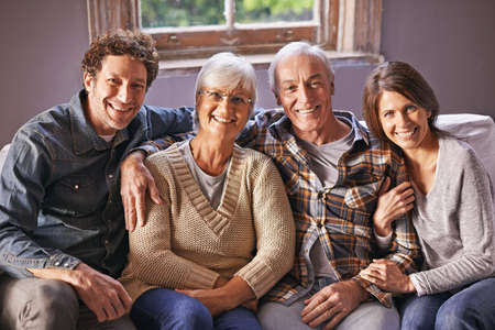 At the in-laws. A portrait of happy mature parents sitting with their adult children at home.