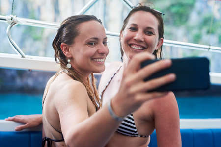Time for another holiday selfie along the sea. Cropped shot of two young woman taking a selfie while on holiday.の写真素材