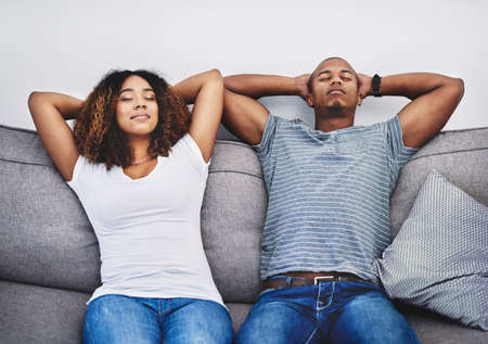 Take time to take a timeout. Shot of a young couple resting on a couch at home.の写真素材