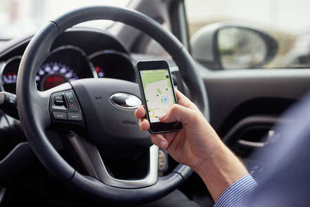 Let your GPS guide you. Closeup shot of a driver in a car using a cellphone to find directions.