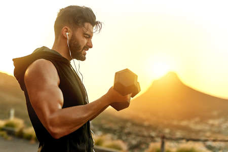 Lifting in the great outdoors. Shot of a young man exercising outdoors.の写真素材