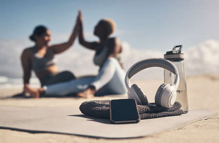 This is all you need to have a good workout. Shot of a cellphone, headphones, towel and water bottle on the beach.の写真素材
