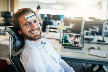 He is one happy camper. Shot of a cheerful young businessman with a sticky note on his forehead...