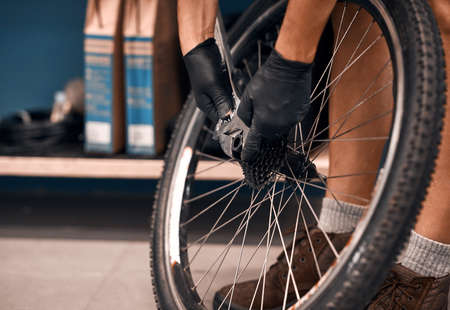 Hell get your wheels on the road again. Cropped shot of a man repairing a bicycle in a workshop.の写真素材