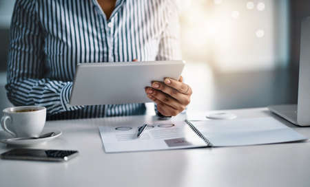 The internet opens many avenues for great opportunities. Closeup shot of an unrecognizable businesswoman working on a digital tablet in an office.の写真素材