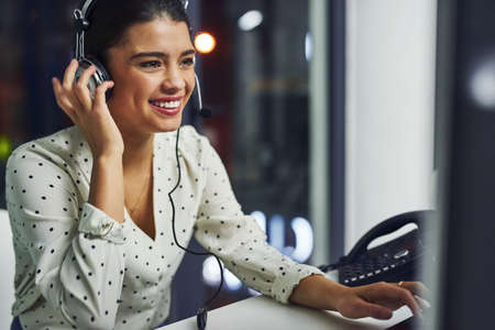 Every call is dealt with professionalism. Shot of a young call centre agent working late in an office.の写真素材