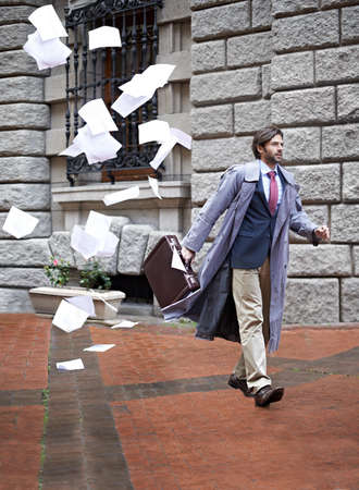 Its not going to be his day.... A businessman unaware that as he walks to work hes losing all his papers.の写真素材
