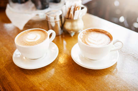 Are those for me. High angle shot of two perfectly presented cups of cappuccino in a coffee shop.の写真素材