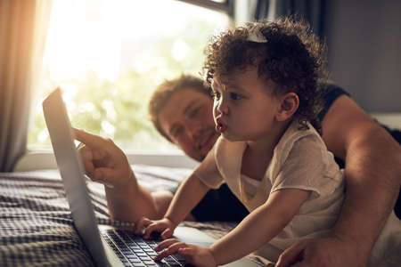 Whats this. Cropped shot of a father showing his baby daughter something on his laptop.の写真素材