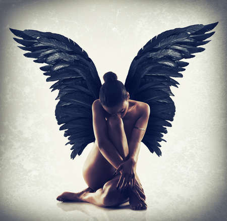 Poise in the stillness. Shot of of naked woman with wings spreading out behind her back.の写真素材