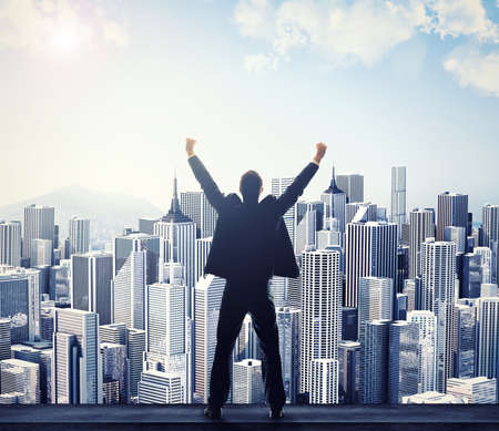 Ive finally made it. Rear view of a businessman with his arms raised while looking at a cityscape.の写真素材
