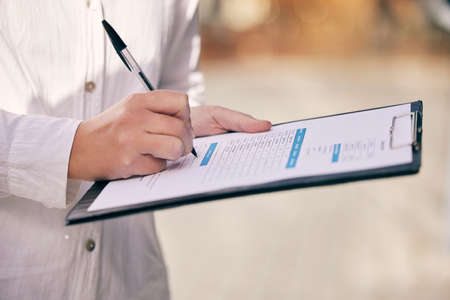 This is where I sign my name. Cropped shot of a woman writing on a form while standing outside.
