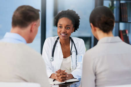 Ill take good care of you. Cropped shot of a female doctor talking to a married couple in her...