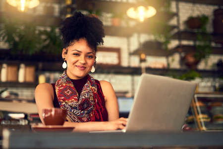 Im working on some fresh ideas for my blog. Portrait of an attractive young woman working on her laptop in a cafe.の写真素材