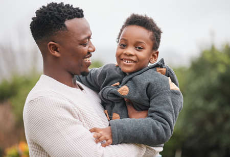They love spending quality time together outdoors. Portrait of an adorable little boy being carried by his father while bonding together outdoors.の写真素材