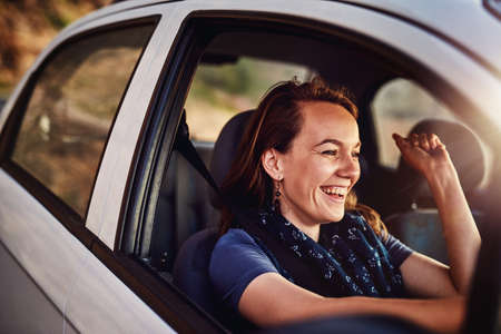 On a solo roadtrip. Cropped shot of a young woman driving in her car.の写真素材
