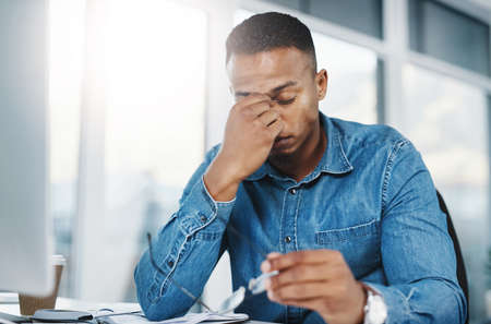 Today has been a disaster to say the least. Shot of a young handsome businessman in a modern office.の写真素材