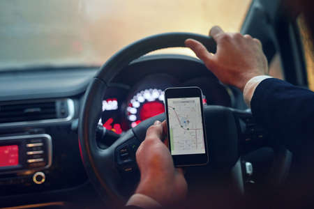 Finding his way on the road. Shot of a businessman using his a gps map while driving.