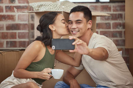 This home is filled with love. Shot of a young couple taking a selfie while sitting in their new home.の写真素材