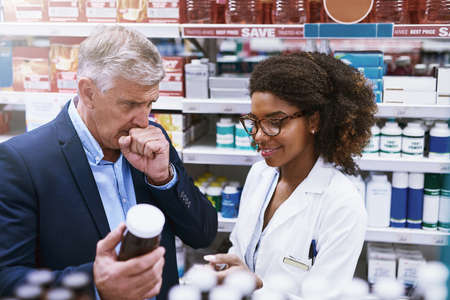 This will clear your throat. Shot of a helpful young female pharmacist helping a customer with choosing the right medication in the pharmacy.の写真素材