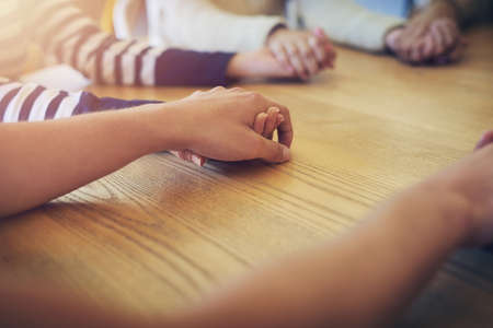 Directing their thoughts to a higher power. Shot of a group of unidentifiable friends joining their hands in solidarity.の写真素材